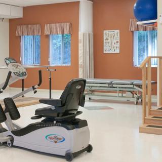 A rehabilitation center therapy room equipped with a stationary bike and other exercise equipment.