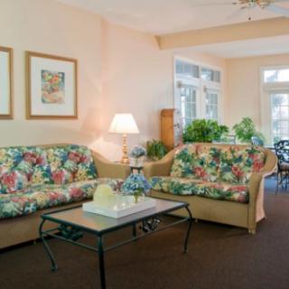 Cozy living room with floral couches and plenty of natural light.