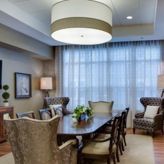 A well-appointed dining room featuring a large table surrounded by chairs, elegant lighting, and airy curtains.