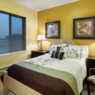 A cozy bedroom with a neatly made bed, decorative pillows, and framed artwork on the walls.