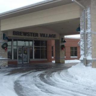 Snow-covered entrance to Brewster Village building during winter.