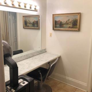 A well-lit vanity table with a mirror and wall art in a cozy corner.