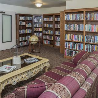 A cozy library reading area with bookshelves, a sofa, and a coffee table.