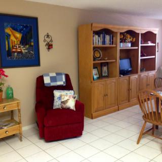 A cozy living room with a red armchair, wooden bookshelf, and decorative elements.