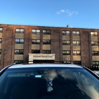 A car parked in front of a brick building under a clear blue sky.