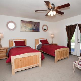 A cozy bedroom with twin beds, red bedding, and a ceiling fan.