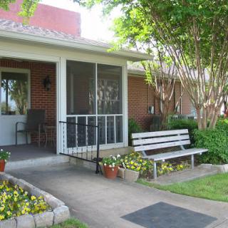 A welcoming front porch with a bench and blooming flowers, inviting relaxation.