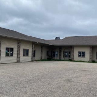 Exterior view of a single-story commercial building with a paved driveway on a cloudy day.