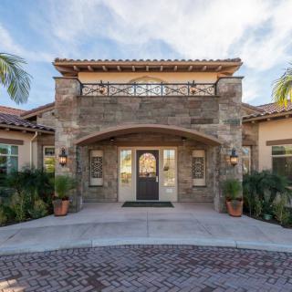 A beautiful entrance to a stone facade house surrounded by palm trees.