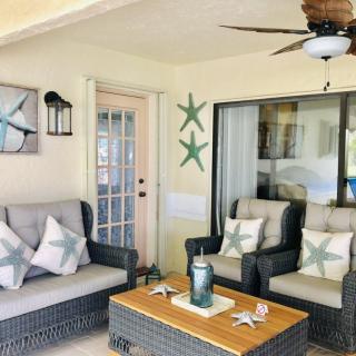 A cozy patio with wicker furniture, starfish decor, and a coffee table under a ceiling fan.