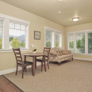 A cozy living room with a small dining set and a sofa by the windows.