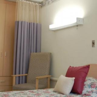 A hospital room with a bed, chair, and curtain.
