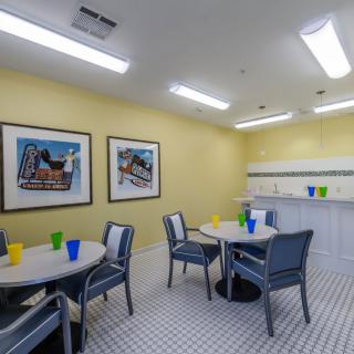 A brightly lit indoor dining area with tables and chairs, decorated with colorful cups and artwork on the walls.