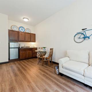 A cozy living space with a kitchen area, featuring a sofa, dining table, and a bicycle wall decoration.