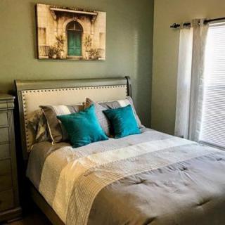 A cozy bedroom featuring a neatly made bed, decorative pillows, and a framed artwork above the headboard.