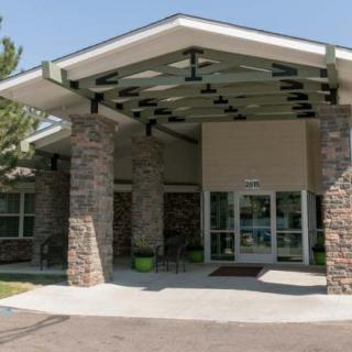 An entrance to a building featuring stone pillars and glass doors, with a large roof overhang.