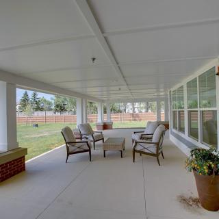 A spacious covered patio with comfortable seating and a view of the garden.