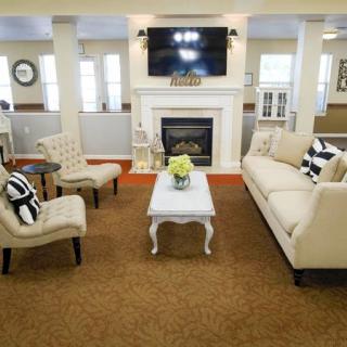 A cozy living room with elegant furniture, a fireplace, and a television mounted above.