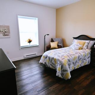 A cozy bedroom with modern decor featuring a single bed, wooden floor, and soft lighting.