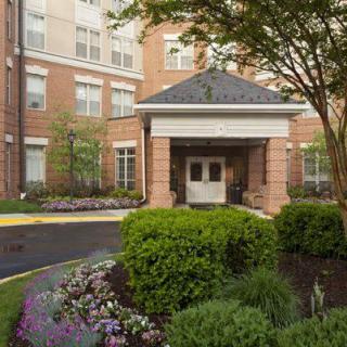 A well-maintained building entrance surrounded by lush landscaping and colorful flowers.