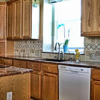 A kitchen with wooden cabinets, a granite countertop, and a window above the sink.