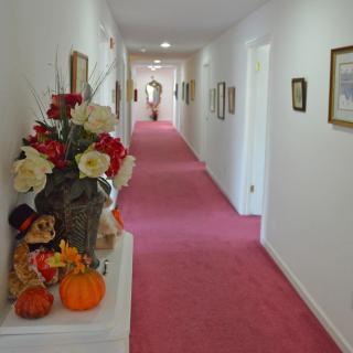 A long hallway with red carpet and autumn-themed decorations, including flowers and pumpkins.