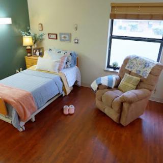 A cozy bedroom setup featuring a neatly made bed, a comfortable armchair, and soft lighting.