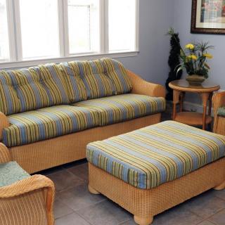 A cozy living room with a striped sofa, armchair, and ottoman set, complemented by indoor plants and a side table.