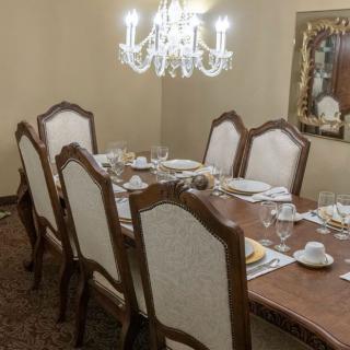 An elegant dining room featuring a set table beneath a chandelier.