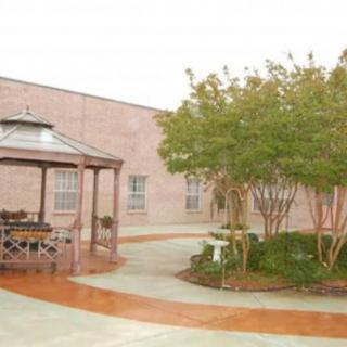 A serene courtyard featuring a gazebo and surrounding trees in front of a brick building.