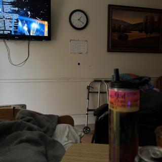 A cozy room featuring a television, clock, and a colorful beverage on the table.