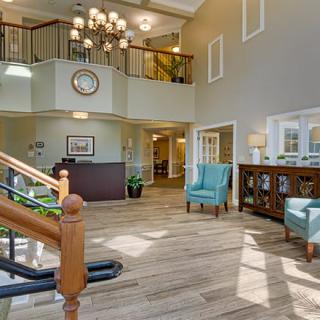 A modern and welcoming lobby area with a staircase, chandelier, and comfortable seating.