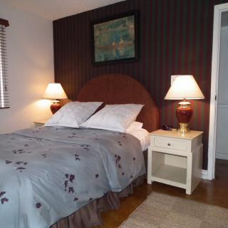 A cozy bedroom with a neatly made bed, two nightstands, and decorative lamps.