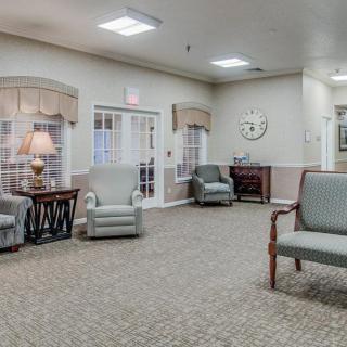A spacious, well-lit living room area with comfortable seating and a large clock on the wall.