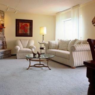 A cozy living room featuring a striped sofa, armchair, glass coffee table, and warm lighting.