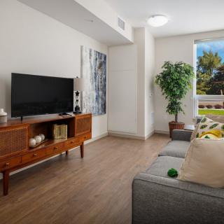 A modern living room with a stylish TV stand, comfortable sofa, and large window bringing in natural light.