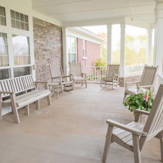 A welcoming porch with wooden rocking chairs and benches, perfect for relaxation.