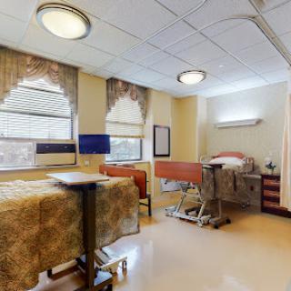 A view of a hospital room featuring beds and essential furniture.