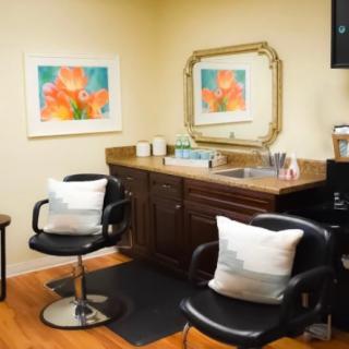 A cozy hair salon interior with chairs, a mirror, and decorative elements.