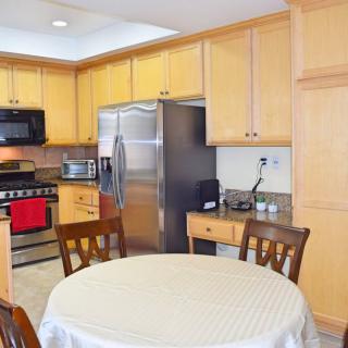 A modern kitchen with wooden cabinets, stainless steel appliances, and a dining table set.