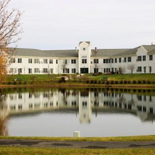 A large building with a pond in the foreground reflecting its image.