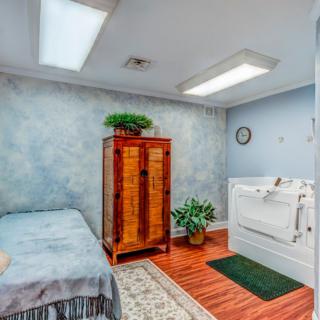A cozy room with a bathtub, bed, wooden cabinet, and decorative plants.