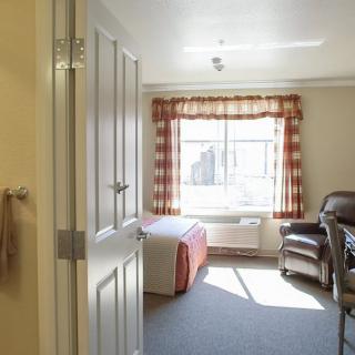A bright bedroom with a bed and chair in natural light.