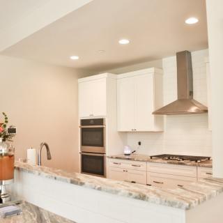 A modern kitchen with white cabinets and stainless steel appliances.