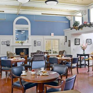 A cozy dining room with neatly arranged tables and chairs, featuring blue walls and white trim.