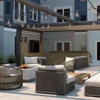 A stylish outdoor patio with comfortable wicker seating and a cozy fire pit, enhanced by ambient string lighting.