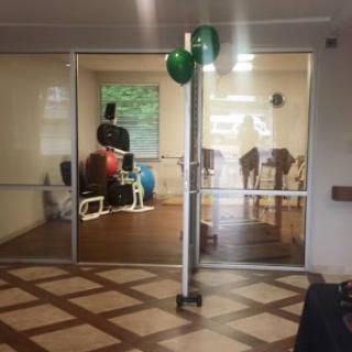 A view into a gym area featuring exercise equipment and decorated with green balloons.
