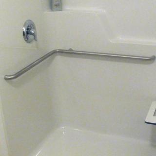 A bathroom with a safety grab bar installed in the shower area.