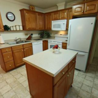 A cozy kitchen with wooden cabinets, a central island, and various appliances.