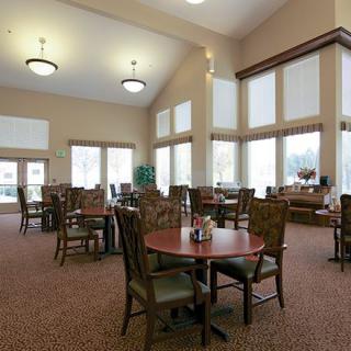 A spacious dining area with multiple tables and chairs, featuring large windows and high ceilings.